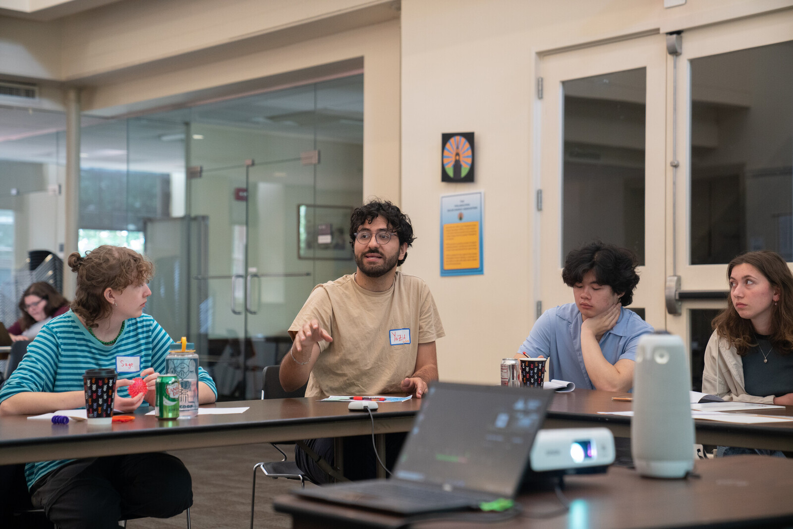 4 people sitting at a long table, with laptop in foreground