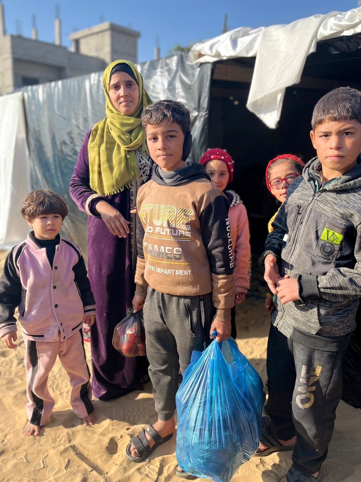 5 children and one woman stand outside of tent