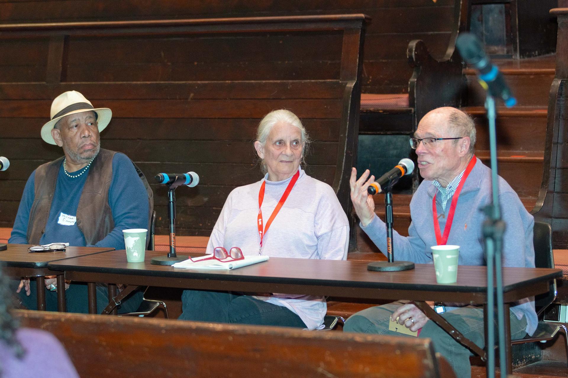 Three people sit at a table addressing an audience. 