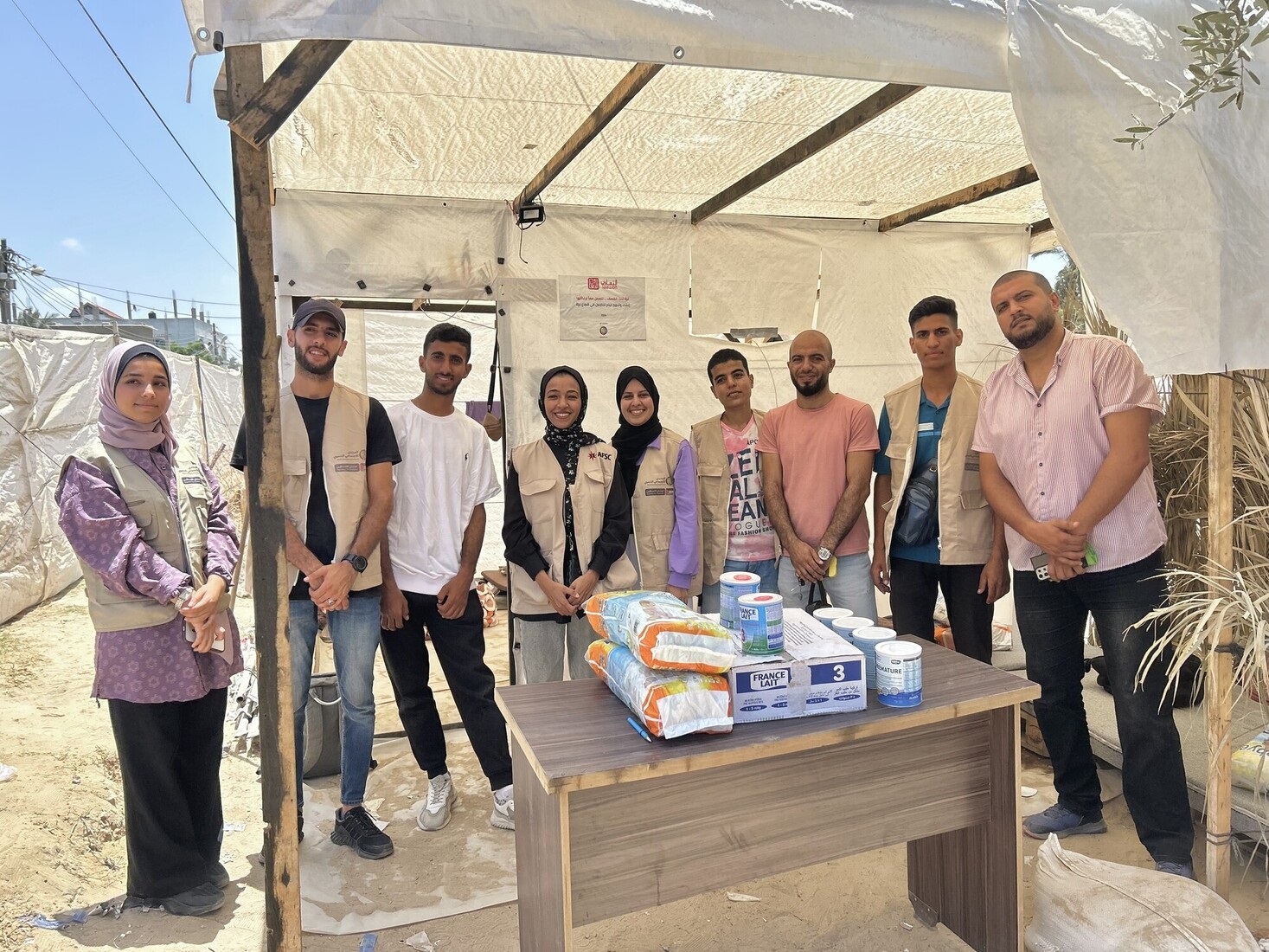 Group of people standing shoulder to shoulder under a tent