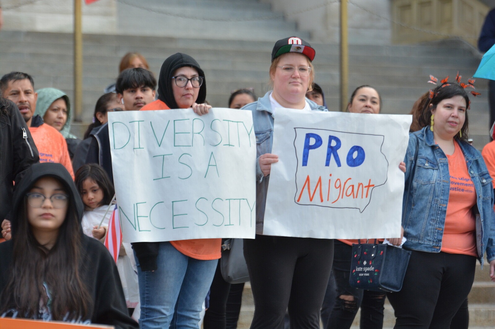 2 people hold signs. One says 