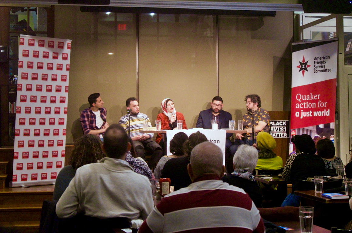 Five people present at a table in front of an audience