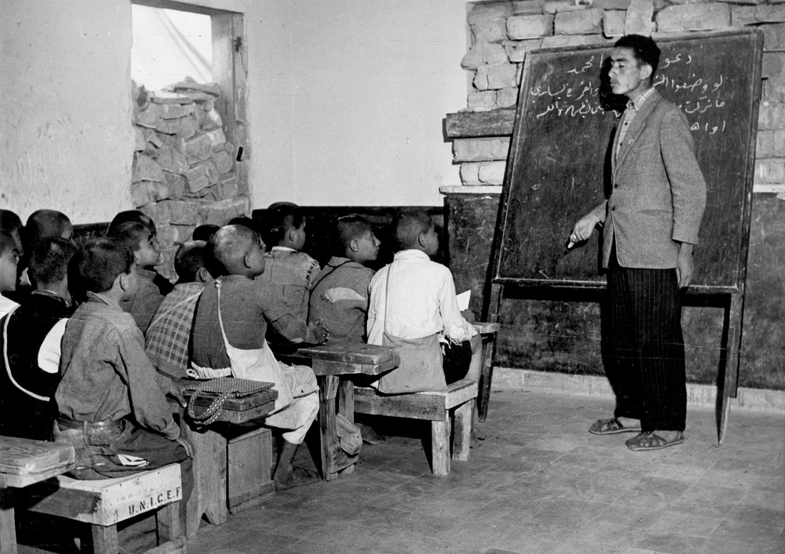 Man teaching a classroom of young students.