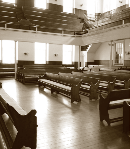 Sepia tone meetinghouse with benches and a balcony