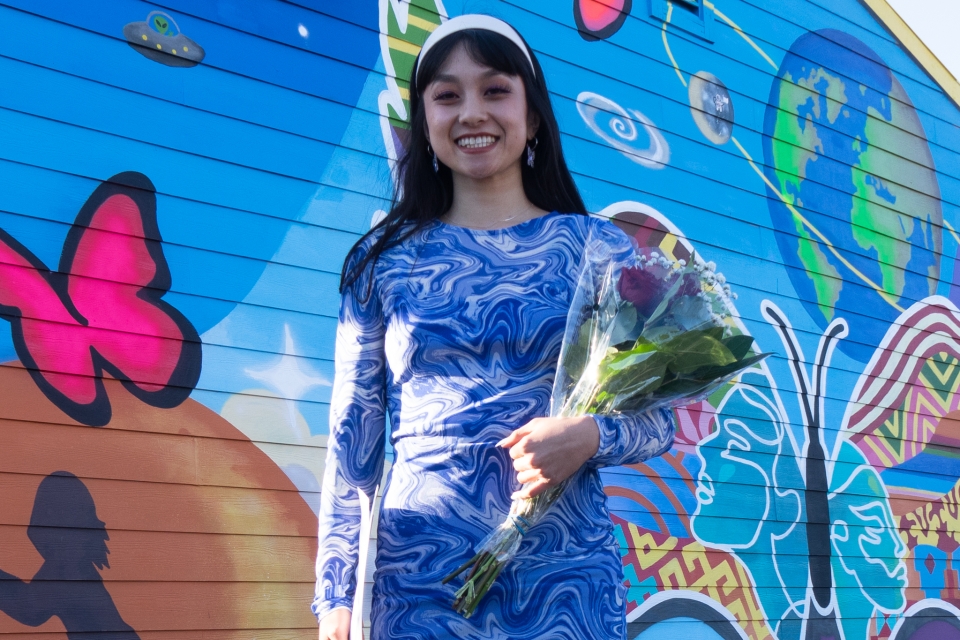 Hana holds a bouquet of roses and smiles at the camera.